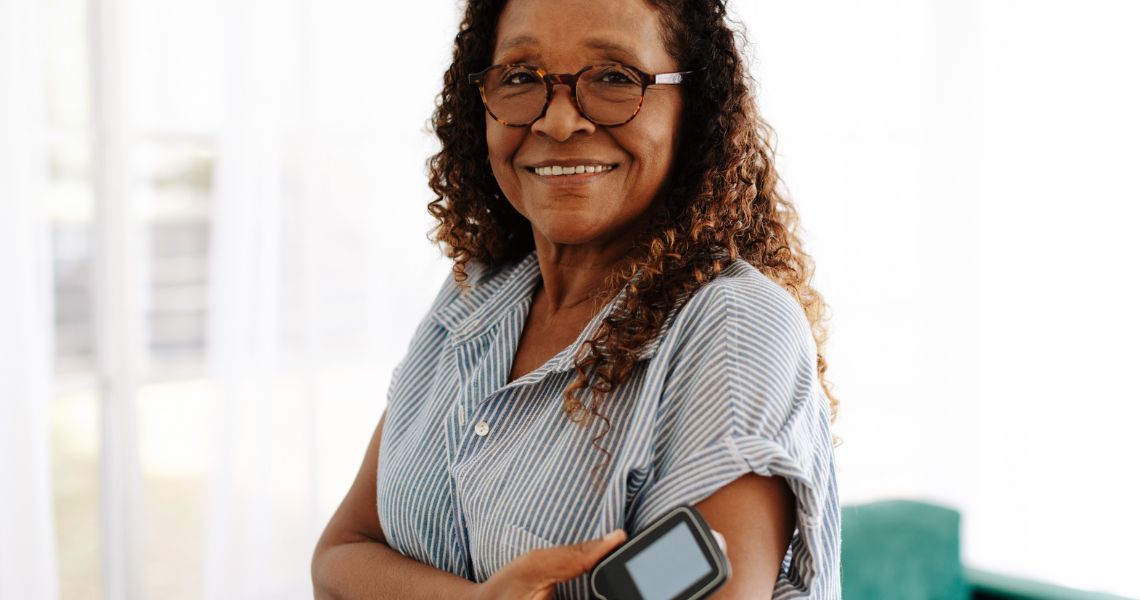 woman with glasses on holding a blood sugar monitor