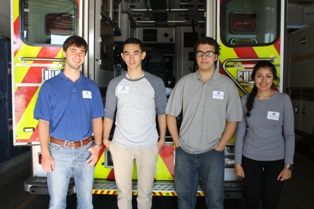 EMT students in front of the back of an ambulance