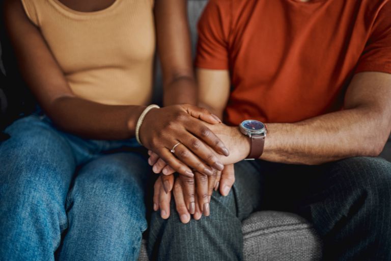 couple sitting touching hands
