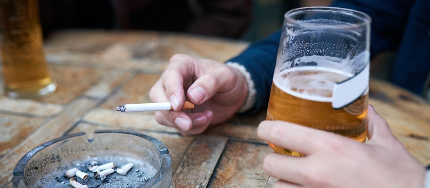 hands holding a cigarette and a beer