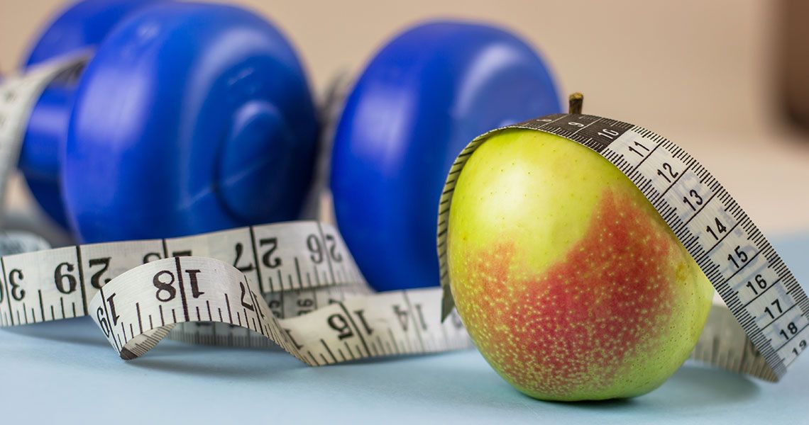 An apple, measuring tape and hand weights