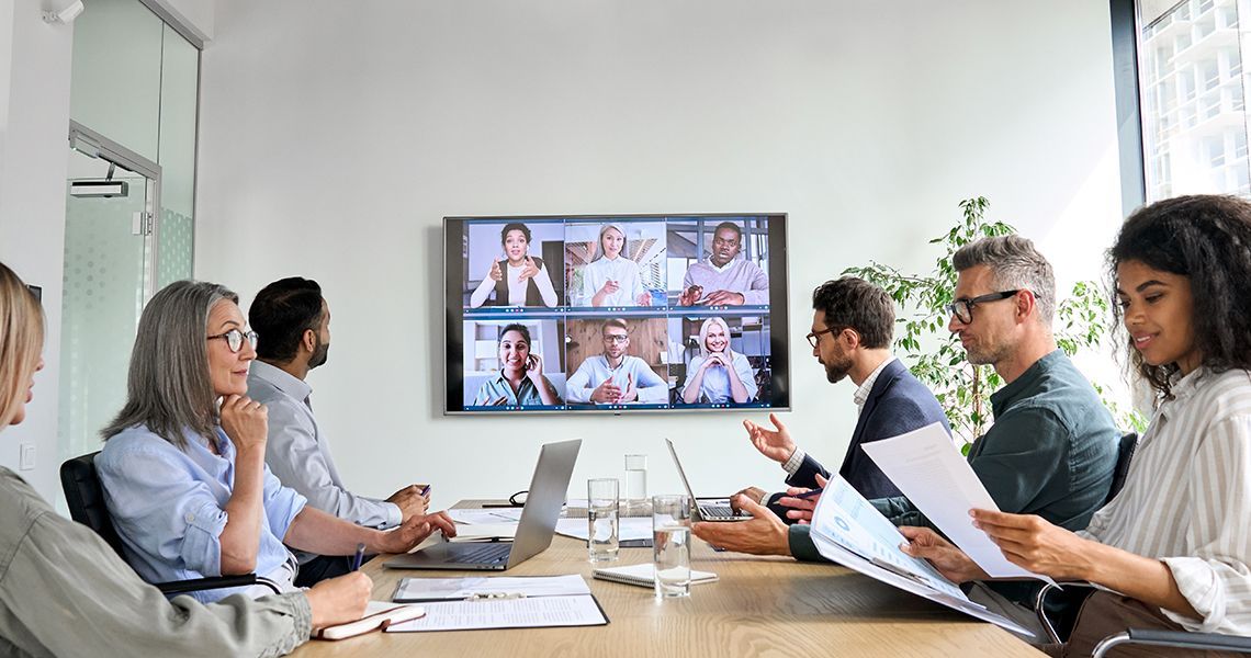 People in a meeting room with a video call on a tv