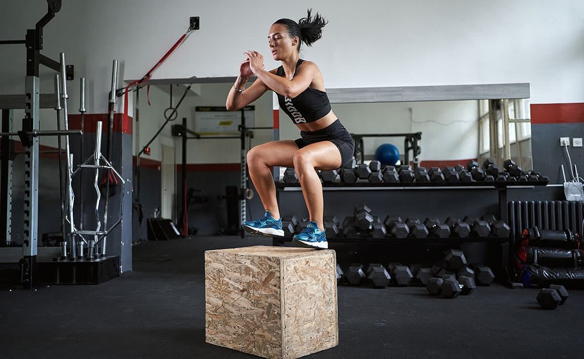 A woman performing a plyometric box jump