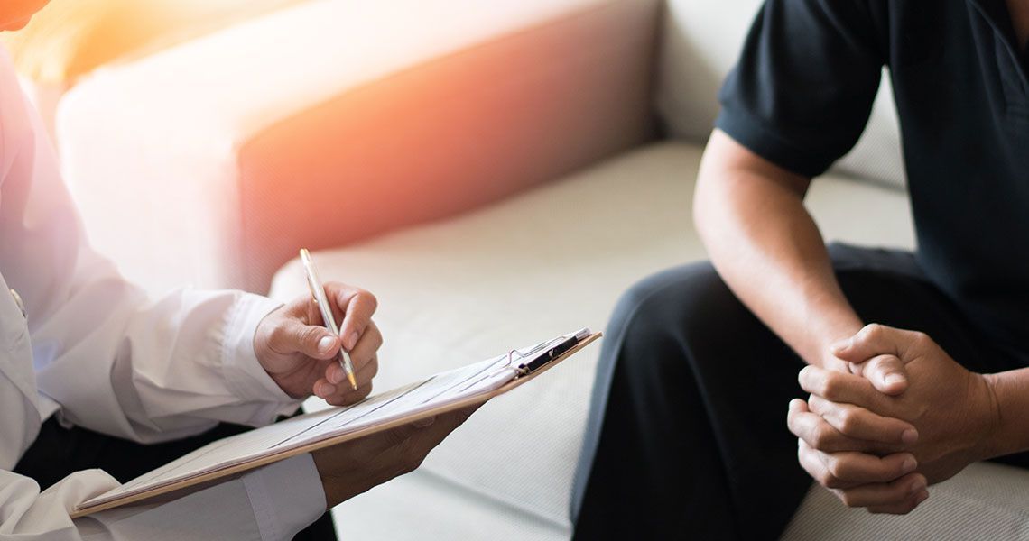 Doctor sitting with a patient and writing notes