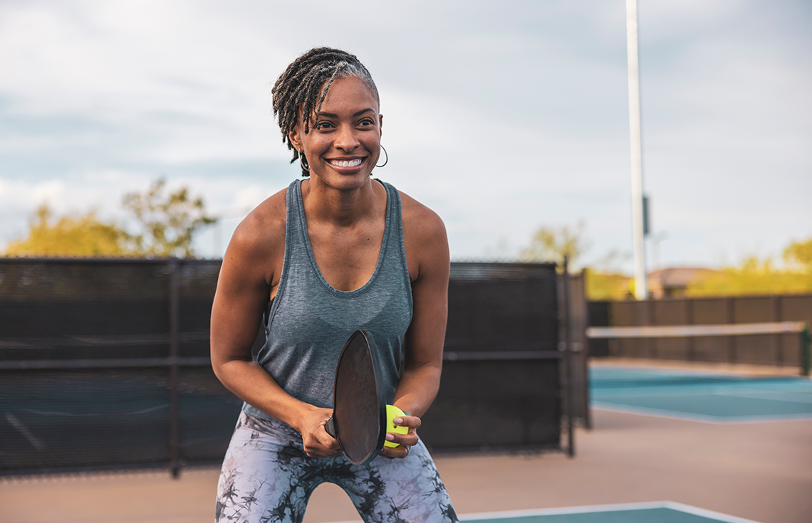 person smiling and playing pickleball