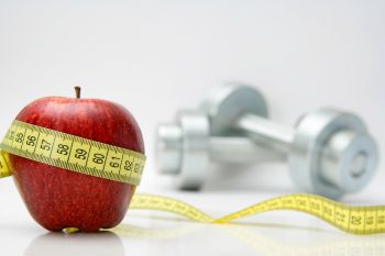 An apple on a white table with weights