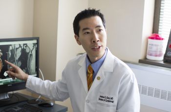 Andrew Choi, MD, points at a computer screen that has an image of a heart.